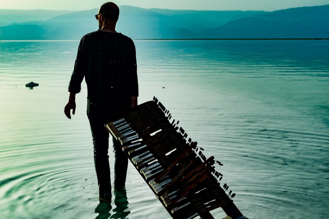 Shai Maestro mit einer kaputten Klaviertastatur am Strand, Promofoto