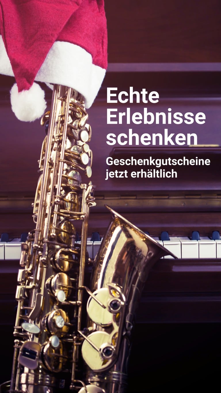 Saxophon auf einer Klavierklaviatur mit Weihnachtsmütze, Hintergrund unscharf, Motiv für Geschenkgutscheine des Jazzfest Bonn.